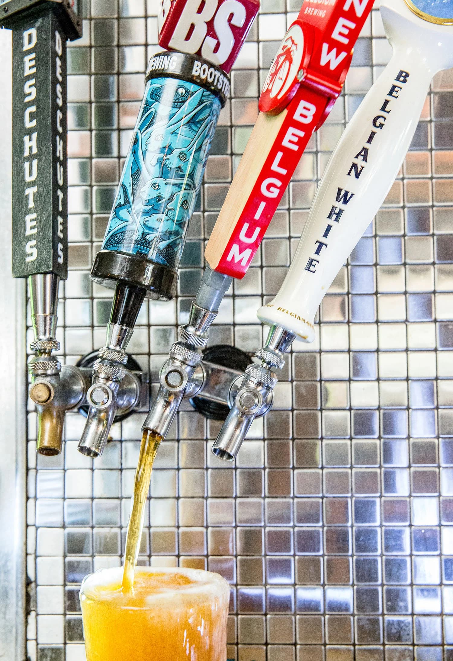 Beer pouring from a row of craft tap handles behind the bar